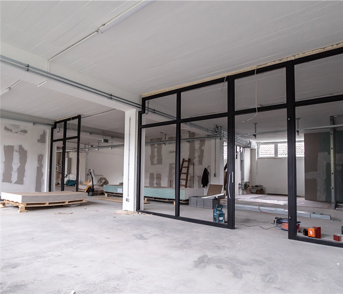 Image showing a incomplete construction site with white walls and floors and black framing for office windows in the middle