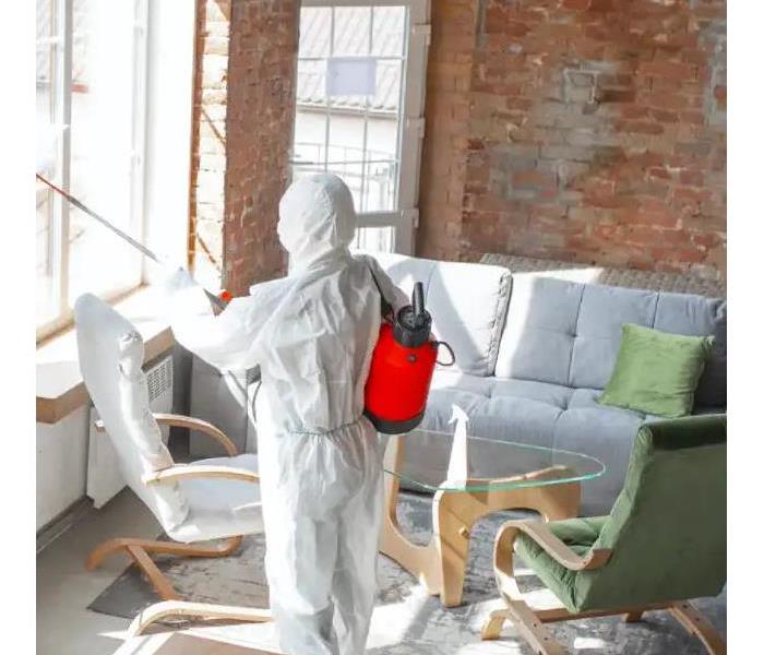 "person spray cleaning, in a hazmat suit, in a brick room"