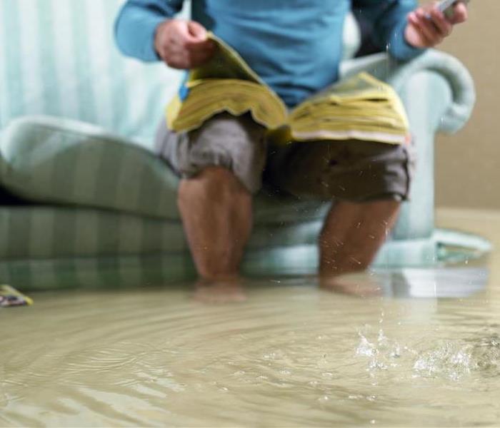A man sitting on a couch in standing water.